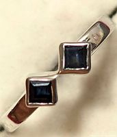 Close-up front view of silver ring with two square black stones set side by side.