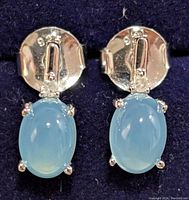 Front view of silver clip-on earrings with oval blue chalcedony stones and small diamond accents.