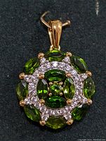 Front view of the silver-tone pendant with green chrome diopside stones and accent diamonds on a dark background showing shape, color and setting details.