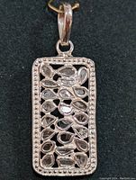 Front view of silver rectangular pendant showing the pear-shaped diamonds and beaded border.