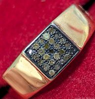 Close-up of the ring's square diamond cluster top showing diamond details and silver band.