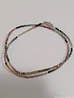 Full view of the multi color sapphire bead necklace laid out to show colors and length.