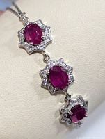 Close-up image showing a section of the silver bracelet with oval ruby stones surrounded by cubic zirconia in a floral-shaped setting.