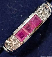 Close-up of ring top showing three square rubies flanked by small round diamonds.