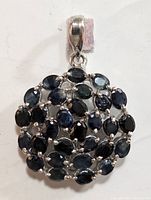 Close-up front view of silver pendant with multiple oval sapphires in cluster design