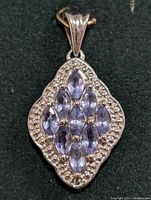 Front view of silver pendant displaying the seven marquise-cut tanzanite stones and detailed silver bead border.