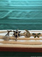 Front view of all 4 vintage animal rings on display showing whale tail, turtle, bird, and butterfly designs.