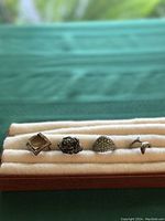 Front view of all four vintage sterling silver rings arranged in a row showing different designs and stones.
