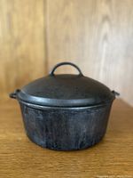 Front view of the vintage Wagner cast iron crock pot with lid on a wooden surface.