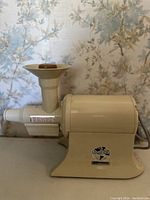 Side profile view of vintage The Champion Juicer showing motor housing, feeding tube with funnel, and juice spout