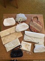 Overview of nine vintage women's handbags and purses displayed on wooden surface showing variety of styles and materials