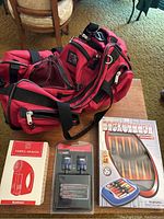 Photo showing the red vintage duffel bag next to boxed fabric shaver, electronic adapters, and boxed backgammon game.