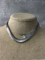 Front view of a solid sterling silver choker necklace shaped like a hook, displayed on a bust.