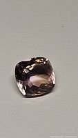 Single 5.42ct cushion cut ametrine gemstone with a visible gradient from purple to golden hues shown against neutral background.