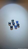 Eight round blue sapphire cabochons arranged on white surface, highlighting size and color variations.