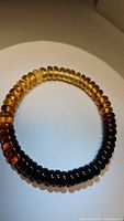 Photo of a Baltic amber bracelet showing a gradient of colors from light to dark amber beads arranged in a circular form on a light background.