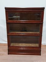 Front view showing three drop-front glass shelves in stacked oak barrister bookcase