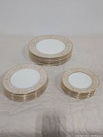 Three stacks of plates showing different sizes: large dinner plates, medium salad plates, and smaller bread and butter/dessert plates with gold decorative border.