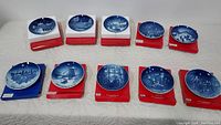 Set of 10 Bing & Grondahl Christmas collector plates displayed on boxes in two rows on a white cloth-covered table.