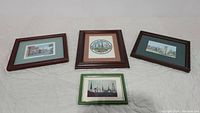Four framed art prints displayed on a white surface, showing varying frame styles and mat colors.