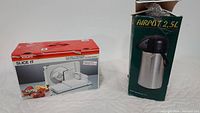 Krups electric food slicer and 2.5L airpot in original boxes displayed on white fabric background.