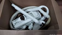 Lux Legacy vacuum cleaner and hose coiled inside box