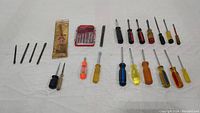 Overview of 16 assorted screwdrivers in varying types, sizes, and handle colors arranged on white background.