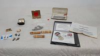 Overview of the lot showing multiple small items including coins, jewelry, Elvis Presley collector set with certificate, rolled coins and various small pieces.