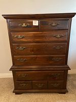 Front view of the wooden tall dresser showing all drawers and brass handles.
