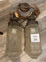Pair of vintage hanging swag pendulum lamps lying on floor showing full length and chain with brass top caps.