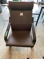 Front view of dark brown office chair showing padded seat, backrest, and headrest with wooden armrests.