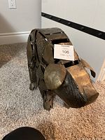 Front and side view of metal pig statue on carpeted floor, showing its assembled metal panel construction and distinct snout and ears.