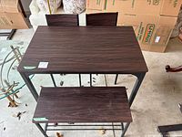 Full view of the rectangular dining table with a bench in front and two chairs behind, all with black metal frames and dark brown wood-grain tops/seats/backs.