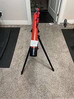 Front view of red Tasco 44TR telescope mounted on tripod showing the front lens end and part of the tripod legs.