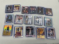 Overview of entire lot showing all 16 basketball cards in protective sleeves spread on a table