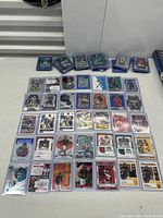 Layout of 39 football cards placed on a white table, most in protective sleeves. Players visible include Ja'Marr Chase, Trevor Lawrence, CJ Stroud, among others.