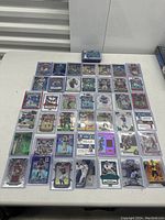 Wide view of 47 football cards laid out on a white table, including various player card types and designs, all in protective sleeves.