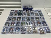 Full lot of baseball cards arranged on table, showing holographic and clear protective casing