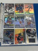 Photo showing nine Wayne Gretzky hockey cards in protective sleeves including holographic and foil finish cards and a round puck-shaped card.