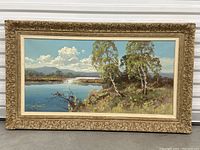 Full view of framed Peter Cox landscape oil painting showing water, trees, distant mountains, and clouds.