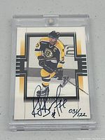 Front view of Ray Bourque autographed Boston Bruins hockey card in plastic case, numbered 034/122.