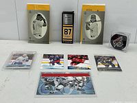 Photo of sports collectible lot items including hockey cards, boxed collectibles and Buffalo Sabres hockey puck arranged on a table.