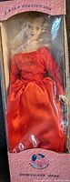 Porcelain doll of Diana Princess of Wales wearing a red satin gown with floral embroidery in original display box with plastic cover.
