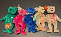 Five Ty Beanie Babies plush bears lined up on a flat surface, showing their front sides and heart tags