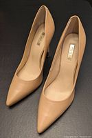 Top-down view of the pair of nude GUESS pumps showing pointed toes and insole logo