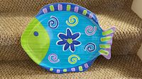Top view of large fish-shaped serving tray with colorful, decorative design in blue, green, yellow, pink, and purple colors.