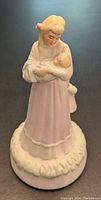 Front view of porcelain figurine showing mother holding infant with detailed facial features and pastel hues.