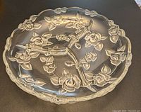 Top view of glass round serving platter with floral embossed decoration and three segmented compartments.