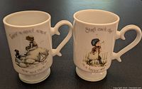 Photo showing both Holly Hobbie cups side by side, each with a different vintage-style illustration and phrase.