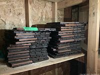 Stacks of wood balcony floor tiles, approximately 30 pieces, stored on shelving in a barn or shed environment.